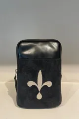 Riñonera negra de cuero con bolsillo frontal de gamuza y bordado de flor de lis en color crema.