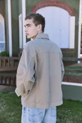 Campera de denim color beige, con cuello amplio, puños con botones y cierre frontal con botones. Incluye bolsillos en el pecho y laterales. Tejido denim de sarga resistente y con protección contra el viento.