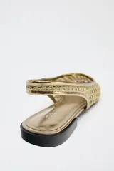 Zapato plano destalonado tipo bailarina color dorado, con capellada de malla trenzada, estilo mule y tira trasera con pieza elástica.