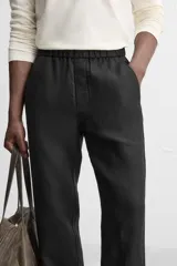 Pantalón negro regular fit confeccionado en tejido de lino. Cintura ajustable con cordón interior, bolsillos frontales y detalle de bolsillos traseros de vivo.