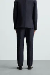 Pantalón de vestir azul marino, de corte recto, confeccionado en lino. Tiene bolsillos laterales y traseros con botón.