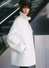 Abrigo blanco de lana virgen con diseño oversize, cuello de solapa y cierre de doble botonadura.