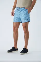 Short de baño celeste con estampado de líneas curvas en azul. Cuenta con cintura elástica con cordón ajustable, dos bolsillos laterales, un bolsillo trasero, suspensor interno y logo bordado.