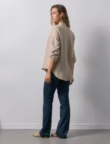 Blusa color beige de poliéster con escote en V y mangas 3/4 regulables con presilla y botón.