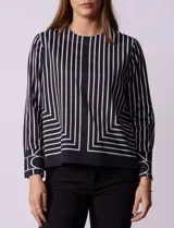 Blusa de gasa estampada a rayas verticales blancas y negras, marca Sioni. Tiene espalda con abertura y botón, y mangas largas con puño y botón.