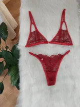 Conjunto de lencería rojo compuesto por un corpiño triangular de encaje con tirantes finos ajustables y una bombacha tipo colaless de encaje con bordes festoneados.