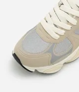 Championes urbanos de running color beige y gris con recortes de cuero sintético y detalles reflectantes.