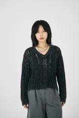 Sweater negro de punto calado con cuello en V y corte holgado. Diseño con efecto desgastado y detalles de hilos rotos, que aporta un estilo vintage.