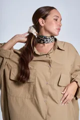 Camisa oversize color beige de manga larga con bolsillos frontales.
