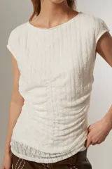 Top blanco de manga corta, con cuello a la base, bordado y frunces. Corte al cuerpo.