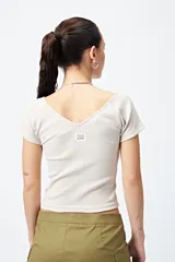Remera cropped color beige, de ribb con escote en V y mangas cortas con terminación de dobladillo.