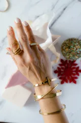 Brazalete abierto dorado de acero quirúrgico con dije de cruz.