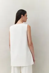 Blusa sin mangas negra de punto suave y fluido, con silueta larga y recta. Presenta botones dorados en los laterales.
