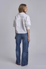 Camisa blanca de mangas 3/4 abullonadas con puños elásticos y cuello clásico.