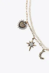 Set de dos collares: uno con cadena metálica con mini perlas y cierre de mosquetón, y otro con cadena de eslabones metálicos y colgantes de charms variados con cierre de mosquetón.