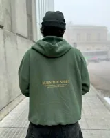 Hoodie verde militar de felpa con frisa gruesa, corte boxy y estampado en la espalda con la frase "BURN THE SHIPS. To fully commit to a course of action, with no possibility of retreat.".