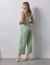 Pantalón de lino color crudo, de corte ancho y tiro alto, con bolsillos laterales y cintura elástica.
