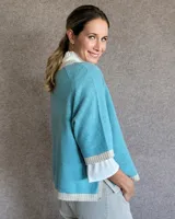 Sweater rosa de lana con cuello redondo y puños y ruedo en color crema.