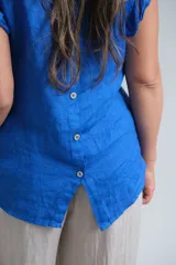 Musculosa azul francia de lino con volados en los hombros y botones de nácar en la espalda.