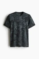 Remera deportiva de poliéster negro con estampado abstracto en tonos grises.