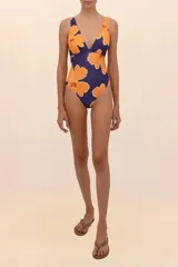 Traje de baño entero con estampado de flores color naranja sobre fondo azul, escote en V profundo, espalda descubierta y cobertura media.