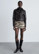 Minifalda de piel bovina con estampado animal print de cebra, tiro medio y cierre lateral con cremallera.