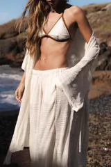 Túnica blanca de lino, con mangas anchas y cuello en V profundo. La prenda se ata a la cintura con un lazo del mismo tejido.