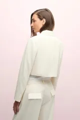 Blazer corto color blanco, de manga larga con solapa y bolsillo de pecho en tela brillosa.