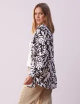 Camisa de lino estampada en blanco y negro con diseño de hojas, marca Zac & Rachel. Tiene cuello con solapa, abertura central con botones, bolsillo aplicado en la parte delantera y mangas largas regulables con presilla y botón.