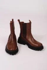 Borcegos de cuero color tostado, con elástico lateral, tirador trasero y suela track negra.