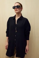 Vestido camisero negro de silueta amplia, con cuello camisero, botonadura frontal completa y mangas largas.