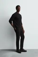 Pantalón de jean negro, corte slim fit, con tiro medio, cinco bolsillos, efecto lavado y cierre frontal con cremallera y botón.