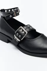 Zapato tipo zueco negro charol con punta fina, doble tira con hebillas metálicas y pulsera al tobillo con tachas.