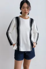 Sweater de punto color blanco con rayas verticales negras y cuello redondo color beige.