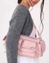 Bandolera rosa claro de cuerina con manija superior y cierre principal. Presenta doble bolsillo frontal y bolsillos laterales, todos con broche lazo con botón para cerrado.