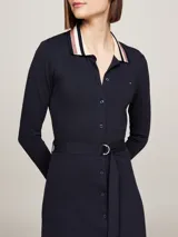 Vestido camisero midi de manga larga color azul marino, con cuello tipo chomba a rayas blancas, rosas y negras. Incluye cinturón con hebilla metálica y logo de Tommy Hilfiger bordado en el pecho.