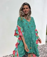 Túnica corta verde con estampado de flores rojas y detalles bordados. Mangas anchas con terminación en volados con estampado floral en tonos rosa y celeste.