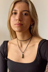 Gargantilla con tira de cuero negro y dije de piedra natural azul en forma de gota.