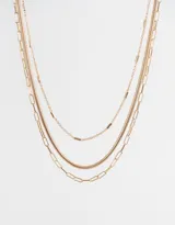 Collar corto dorado de tres capas con diferentes tipos de cadenas de metal.