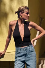 Top negro de cuello halter ajustable con lazadas, espalda descubierta, detalle de aplicación metálica en el delantero y drapeado lateral.