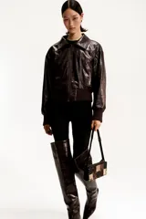 Cartera bandolera rectangular con correa ajustable negra. El cuerpo del bolso está confeccionado con un patrón de patchwork de cuadrados en cuero negro liso, gamuza marrón y estampado de piel de serpiente en tonos beige y marrón. Los paneles están unidos por grapas metálicas doradas. Posee cierre superior y forro interior.