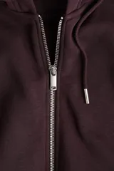 Campera con capucha color borgoña, con cierre frontal y bolsillos tipo canguro. Confeccionada en felpa con interior cepillado suave, hombros caídos, capucha forrada con cordón para ajustar y puños y bajo en punto acanalado.