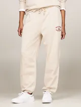Pantalón de jogging color beige, de corte holgado, con cintura elástica ajustable con cordón y logo bordado en rojo.