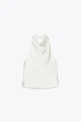 Top blanco de cuello halter con la espalda descubierta y cierre trasero con botones ocultos.