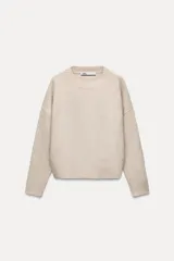 Sweater color beige de punto liso, con cuello redondo y mangas largas.