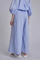 Pantalón palazzo azul marino con bordado de flores blancas en la parte inferior de ambas piernas.