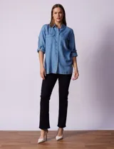 Camisa celeste de tencel con cuello con solapa, abertura central con botones ocultos, bolsillos delanteros y mangas largas regulables con presilla y botón.