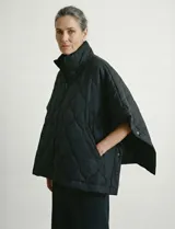 Poncho acolchado color mostaza con cuello alto y abertura frontal con cierre. Presenta un patrón capitoné de formas ovaladas y bolsillos delanteros.