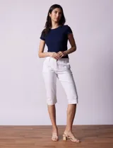 Pantalón capri blanco de algodón elastizado. Pretina con pasadores, botón y cierre. Delantera con bolsillos. Trasera con bolsillos simulados.