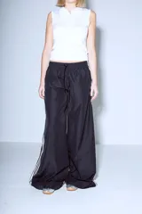 Pantalón Adidas Parachute negro de corte holgado con las tres rayas blancas a los costados.